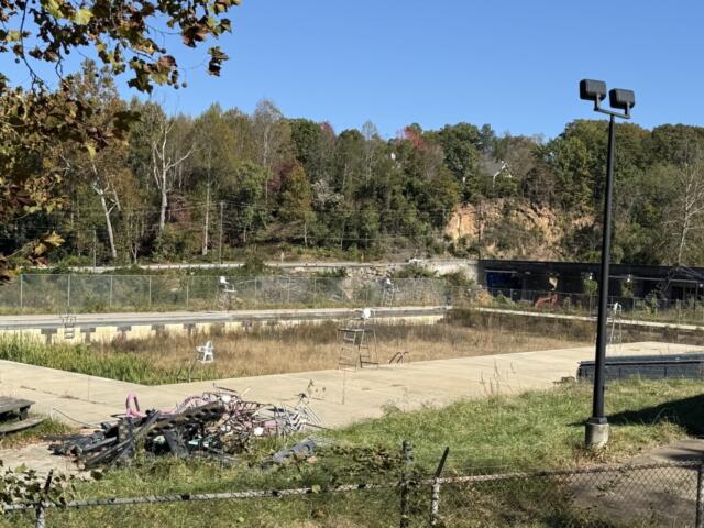 The swimming pool at Asheville's Recreation Park remains closed, with overgrown vegetation and debris visible in the facility. The city received nearly $2.5 million in an earlier round of state grants to help reconstruct the park following Hurricane Helene.