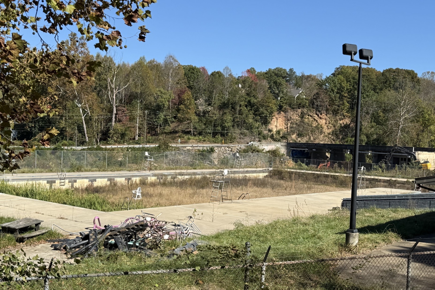 The swimming pool at Asheville's Recreation Park remains closed, with overgrown vegetation and debris visible in the facility. The city received nearly $2.5 million in an earlier round of state grants to help reconstruct the park following Hurricane Helene.