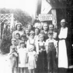 Nora Mae “Aunt Mae” Gilliam stands with children outside the tiny Broad River Community Library, which she operated in rural Buncombe County beginning in 1938. The 12-by-12-foot log building served residents with books and other reading materials.
