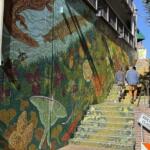 Two pedestrians walk up the colorful Wall Street steps in downtown Asheville, where artist Dayna Walton's "Meander" mural has been expanded onto the adjoining parking garage wall.