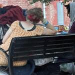 Two people who appear to be experiencing homelessness sit on a bench in Asheville. Concerns about homelessness and public safety in West Asheville have drawn increased attention from residents and city leaders.